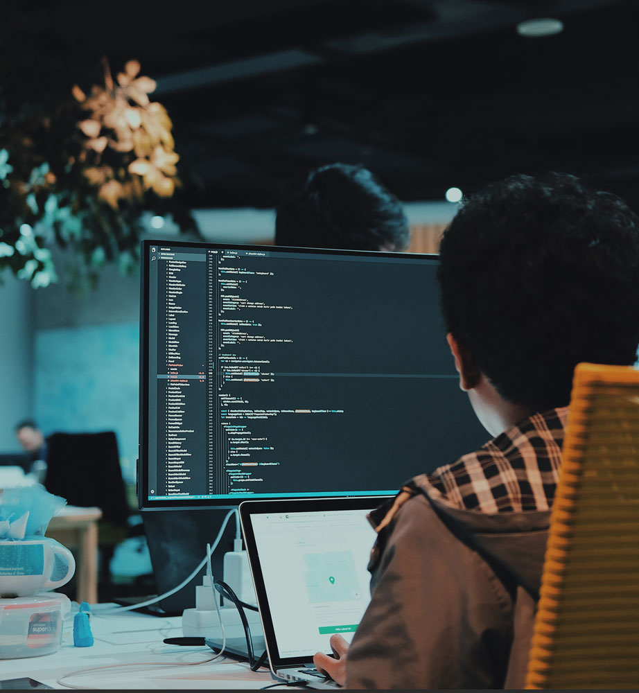 A software developer working at a code-filled monitor